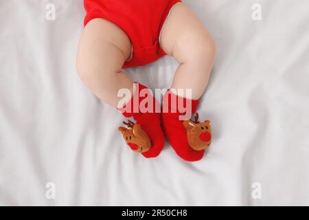 Bambino che indossa calze natalizie festive su lenzuola bianche, vista dall'alto Foto Stock