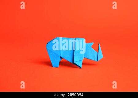 Origami art. Rinoceronti di carta blu chiaro fatti a mano su sfondo arancione Foto Stock