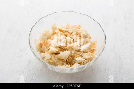 Ciotola di vetro con pezzi di pasta sfoglia per un delizioso dessert arabo umm ali o altro piatto su sfondo grigio chiaro. Fase di cottura Foto Stock