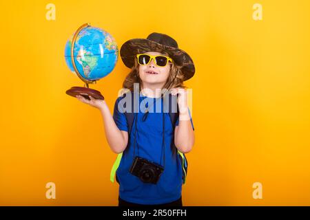 I turisti bambini con zaini e macchina fotografica tengono il mondo isolato su sfondo giallo. Avventura, viaggi e turismo concetto. Little explorer attivo Foto Stock