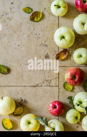 Mele gialle, verdi e rosse e foglie autunnali Foto Stock