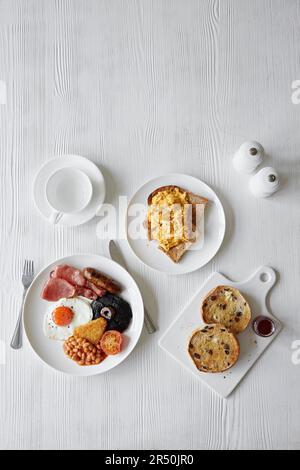 Una colazione inglese completa, uova strapazzate su pane tostato e un panino di frutta tostato Foto Stock