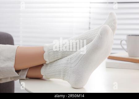 Donna in calze calde relax vicino al tavolo a casa, primo piano Foto Stock