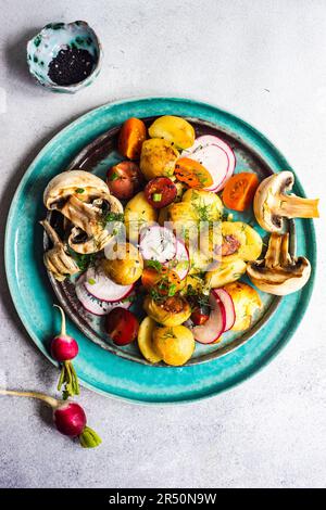 Insalata di verdure di stagione cucita nella ciotola su sfondo di cemento Foto Stock