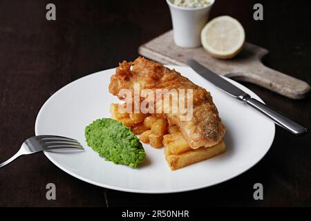 Pesce in pastella e patatine fritte alla birra con piselli funghi Foto Stock