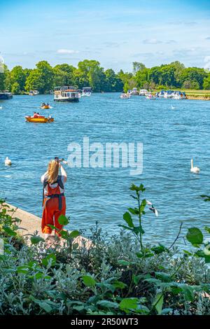 Una vista lungo il Tamigi a Windsor in una giornata all'inizio dell'estate. Una donna si ferma a scattare una fotografia. Foto Stock