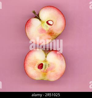 Due mezze mele su sfondo rosa Foto Stock