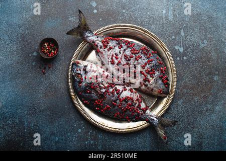 Due orate intere con testa dorata condite con pepe rosa (pronte per la cottura) Foto Stock