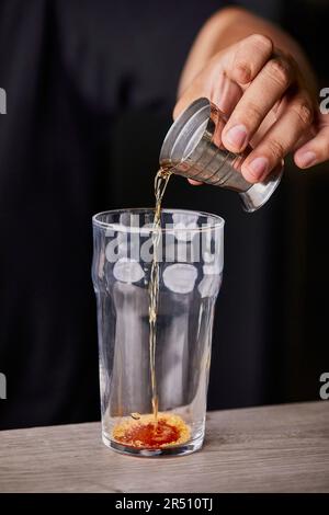 Preparare un cocktail vecchio stile, versare il liquore amaro in un bicchiere Foto Stock