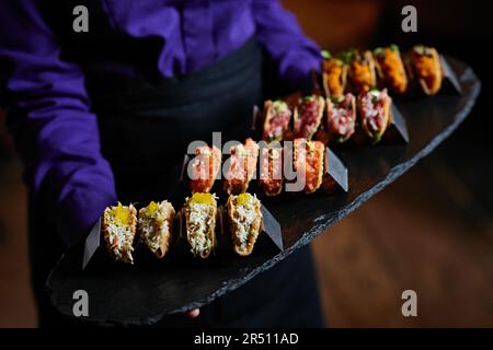 Tacos di pesce assortiti serviti come antipasti su un piatto di ardesia Foto Stock