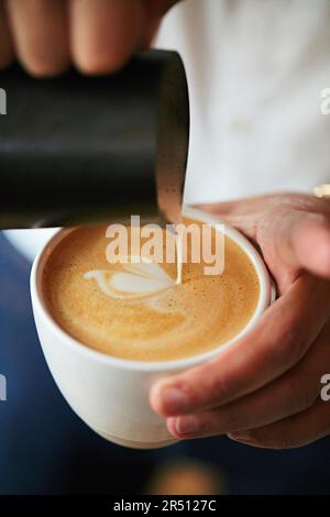 Il barista versa la schiuma di latte con latte art Foto Stock