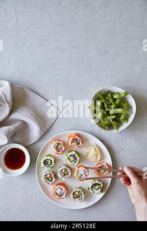 Piatto misto di sushi con bacchette e edamame Foto Stock