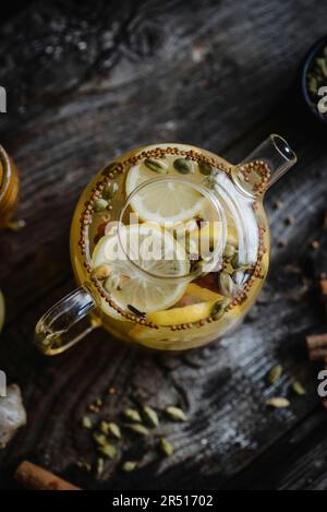 Tè invernale speziato con limone, cannella e cardamomo in teiera di vetro Foto Stock