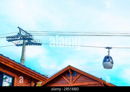 Lo skilift gondola viaggia in alto sopra i tetti di un incantevole villaggio invernale. Foto Stock