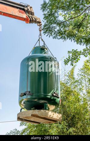 Un serbatoio di gas GPL viene sollevato da una gru e quindi sepolto in un giardino Foto Stock