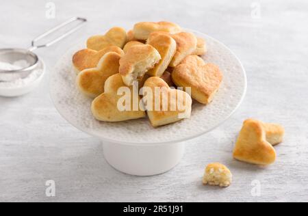 Biscotti cagliati morbidi su un piatto bianco con un filtro di zucchero a velo su sfondo grigio chiaro. Deliziosi biscotti fatti in casa. Foto Stock