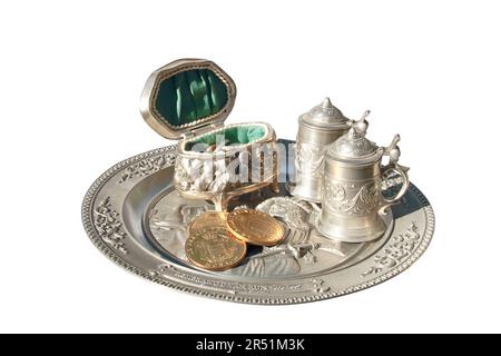 Nella figura è raffigurato un vassoio di metallo intarsiato sul quale si trova una scatola gialla con monete e due piccoli cerchi. Foto Stock