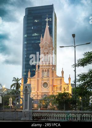 La Cattedrale di Danang in Vietnam è annidata da un alto e moderno edificio di uffici. Foto Stock