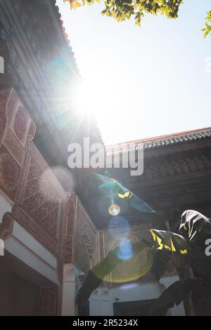 Basso angolo di vecchio edificio con dettagli ornamentali sotto luminosi raggi di sole in luce del giorno sulla strada della città del quartiere di Marrakech Foto Stock