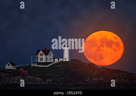 Nubble e la Luna piena - l'iconico e storico Faro di Nubble a Cape Neddick a York, Maine, accanto alla luna piena dei Cacciatori in ascesa. Questo ima Foto Stock