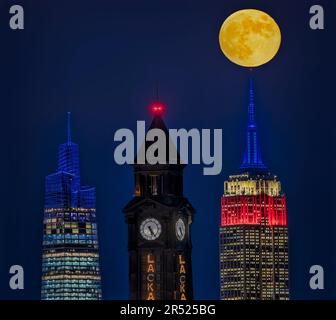 NJ NYC state Lines - la luna piena di Beaver sorge dietro la Torre dell'Orologio di Lackawanna a Hoboken, New Jersey, accanto all'iconico Empire state Building An Foto Stock