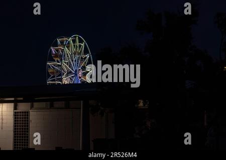 Vista in lontananza di una ruota panoramica illuminata di luce contro il cielo notturno. Foto Stock