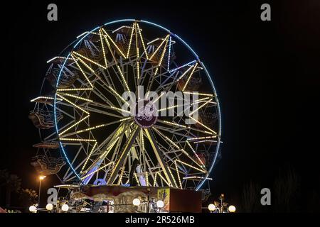 Vista in lontananza di una ruota panoramica illuminata di luce contro il cielo notturno. Foto Stock