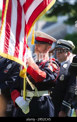 Evento del Memorial Day. Dennis, Massachusetts, (Cape Cod) , Stati Uniti. Un vigile del fuoco guardia d'onore con la bandiera americana Foto Stock