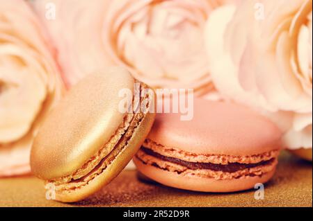 Tenere biscotti francesi macaron su dorati backgrouns Foto Stock