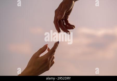 Una mano di donna e di uomo che si avvicinano l'una all'altra Foto Stock