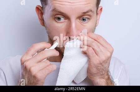 Guy gocciolando gocce nasali nel naso, ritratto, primo piano Foto Stock