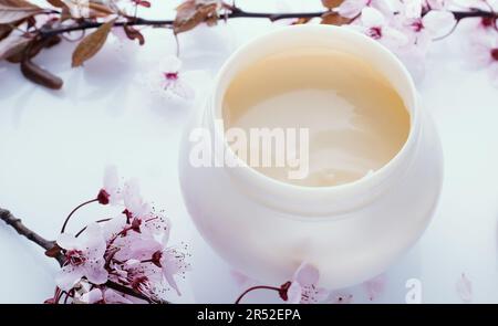 Crema cosmetica e bellissimi fiori, primo piano Foto Stock