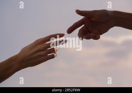 Una mano di donna e di uomo che si avvicinano l'una all'altra Foto Stock