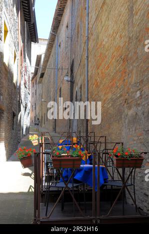 Italia, Italia, Marche, Urbino, centro storico, centro storico, vicolo stretto con tavolo da pranzo, tavolo da ristorante con sedie sul vicolo Foto Stock