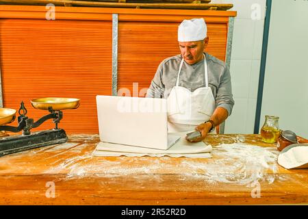 Baker consulenza sul computer, al tavolo di lavoro Foto Stock