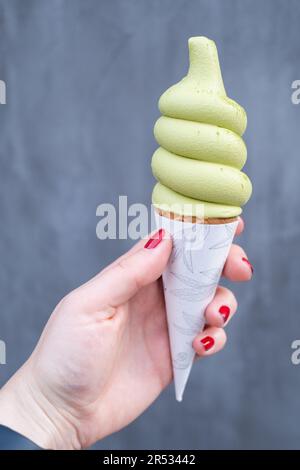 Mano che tiene un tè matcha aromatizzato gelato morbido servire, Tokyo, Giappone Foto Stock