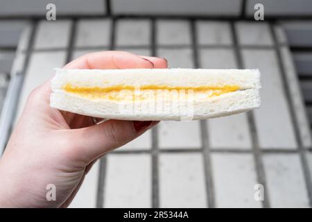 Mano che tiene un sandwich all'uovo di Lawson, Giappone Foto Stock