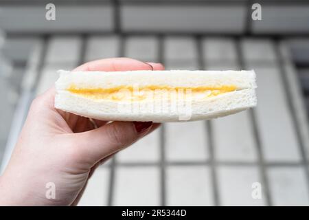 Mano che tiene un sandwich all'uovo di Lawson, Giappone Foto Stock