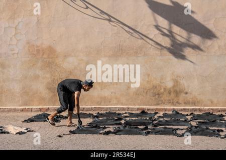 Un uomo si distende ad asciugare davanti alla Moschea ben Youssef, Marrakech, Marocco Foto Stock