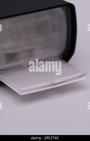 Un flash esterno con diffusore innestato su uno sfondo bianco Foto Stock