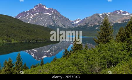 Rising Wolf Mountain - Primavera mattina vista del torreggiante Rising Wolf Mountain che riflette nella calma inferiore due Medicine Lake. Glacier National Park, MT, USA. Foto Stock