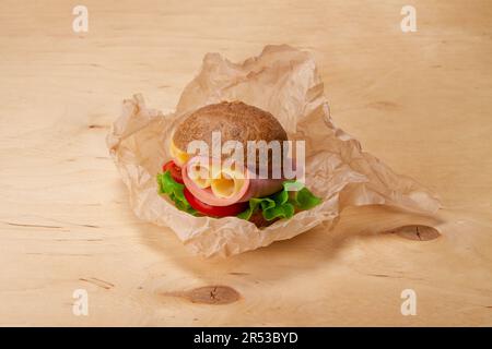 Hamburger sandwich con mortadella, formaggio, lattuga, pomodori su tavola di legno Foto Stock