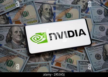 Il logo NVIDIA viene visualizzato sullo smartphone e viene posizionato su un mucchio di fatture in dollari USA. Concetto. Messa a fuoco selettiva. Stafford, Regno Unito, 31 maggio 2023 Foto Stock