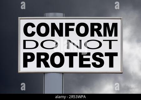 Primo piano su un cartellone bianco contro un cielo nuvoloso con il messaggio "conformità, non protestare" scritto nel mezzo. Foto Stock