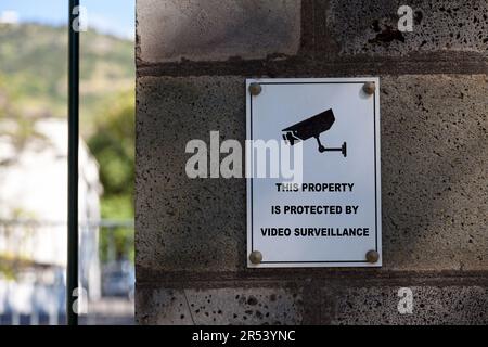 Un cartello bianco su una colonna di pietra che dice "questa proprietà è protetta dalla videosorveglianza". Foto Stock