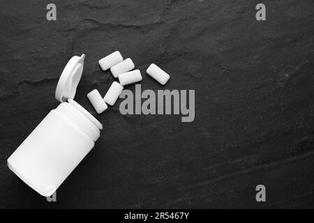 Vaso con gomme da masticare su tavolo nero, piatto. Spazio per il testo Foto Stock