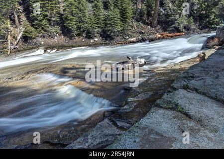 Le rapide del fiume Merced corrono tra pini e grandi rocce nel Parco Nazionale di Yosemite Foto Stock