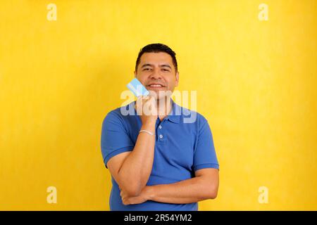 Uomo latino dai capelli scuri di 40 anni mostra la sua carta di credito o debito felice di usarlo in sconti e promozioni in negozio e acquisti online Foto Stock