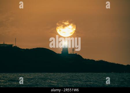 Al crepuscolo il sole si dirige verso l'orizzonte, la sagoma del faro. Fugui Cape Lighthouse è noto per i suoi scatti al tramonto e per l'attrattiva turistica Foto Stock