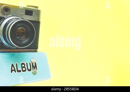 Vecchia macchina fotografica di film d'epoca con album fotografico isolato su giallo pallido Foto Stock